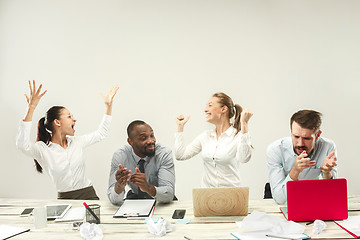 Image showing Young men and women sitting at office and working on laptops. Emotions concept