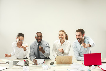 Image showing Young men and women sitting at office and working on laptops. Emotions concept