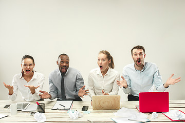 Image showing Young men and women sitting at office and working on laptops. Emotions concept