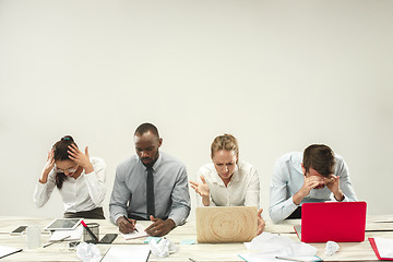 Image showing Young men and women sitting at office and working on laptops. Emotions concept