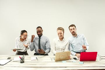 Image showing Young men and women sitting at office and working on laptops. Emotions concept