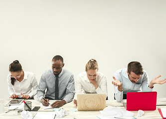 Image showing Young men and women sitting at office and working on laptops. Emotions concept