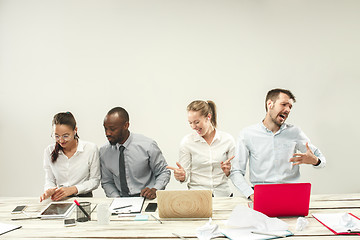 Image showing Young men and women sitting at office and working on laptops. Emotions concept