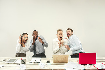 Image showing Young men and women sitting at office and working on laptops. Emotions concept