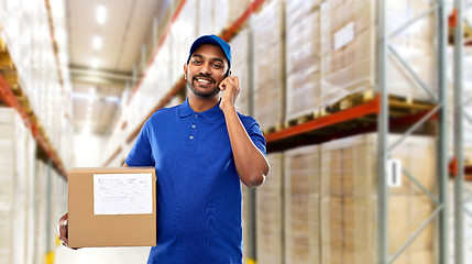 Image showing delivery man with smartphone and box at warehouse