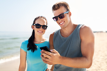 Image showing couple in sports clothes with smartphones on beach