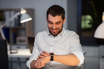 Image showing happy businessman with smart watch at nigh office