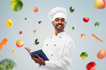 Image showing happy indian chef with cookbook over vegetables