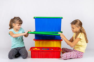 Image showing Two girls opened a large plastic box with toys