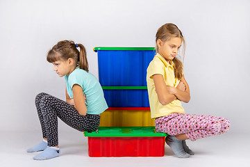 Image showing Two girls quarreled, sit on a box and turned away from each other