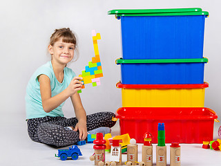 Image showing Girl playing toys, large plastic boxes are standing nearby