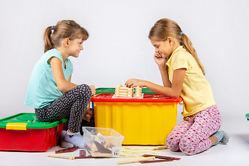 Image showing Two girls collect a house on a box with toys