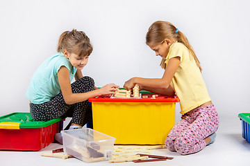 Image showing Two girls are assembling a house on a box with toys, looking in the instructions