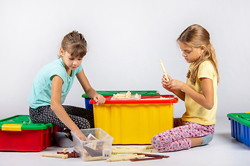 Image showing Two girls collect a house from the designer on a large plastic box