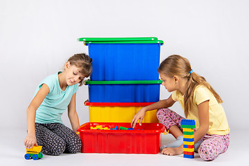 Image showing Two girls opened a box with a designer and start to play toys