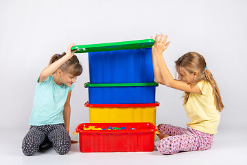 Image showing Two girls opened the lid of a large plastic box with toys, and look inside