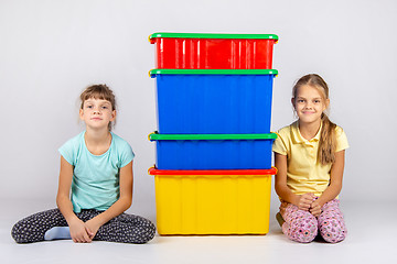 Image showing Two girls are sitting next to four large plastic boxes