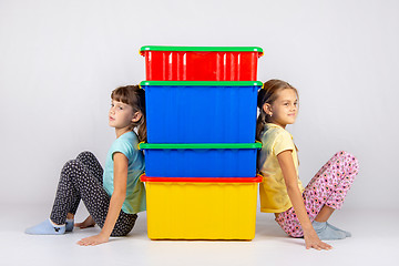 Image showing Two girls from different sides leaned their backs on plastic boxes