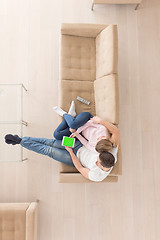 Image showing young couple in living room using tablet top view