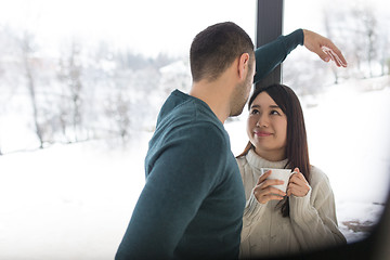 Image showing multiethnic couple enjoying morning coffee by the window