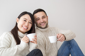 Image showing multiethnic couple enjoying morning coffee by the window