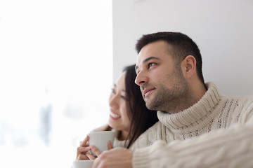 Image showing multiethnic couple enjoying morning coffee by the window