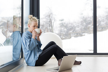 Image showing woman drinking coffee and using laptop at home