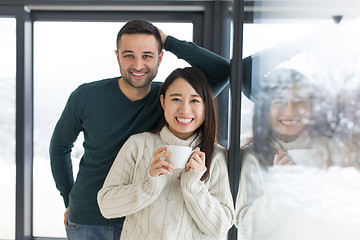 Image showing multiethnic couple enjoying morning coffee by the window