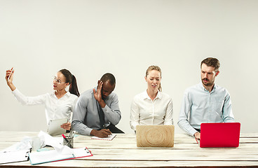 Image showing Young men and women sitting at office and working on laptops. Emotions concept