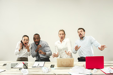 Image showing Young men and women sitting at office and working on laptops. Emotions concept