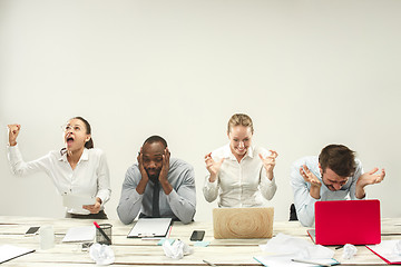 Image showing Young men and women sitting at office and working on laptops. Emotions concept