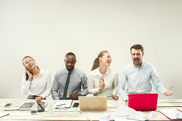 Image showing Young men and women sitting at office and working on laptops. Emotions concept