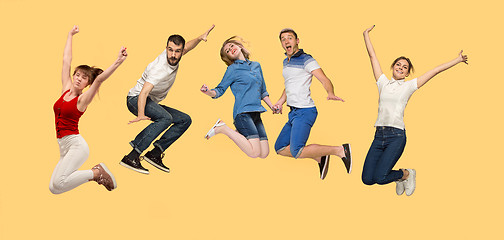 Image showing Freedom in moving. young man and women jumping against yellow background