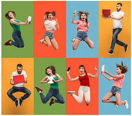 Image showing The happy young jumping women and man with laptops and phone