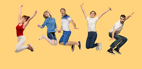 Image showing Freedom in moving. young man and women jumping against yellow background