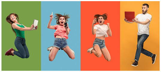 Image showing The happy young jumping women and man with laptops and phone