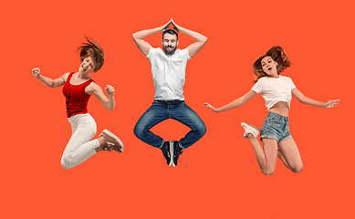Image showing Freedom in moving. young man and woman jumping against orange background