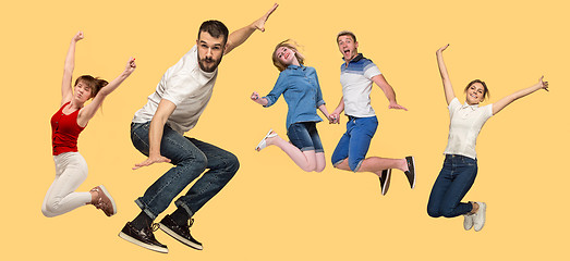 Image showing Freedom in moving. young man and women jumping against yellow background