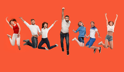 Image showing Freedom in moving. young man and women jumping against red background