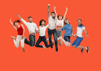 Image showing Freedom in moving. young man and women jumping against red background