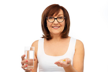 Image showing senior woman with glass of water and pills