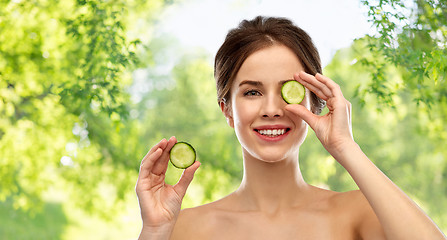 Image showing smiling woman with cucumber over grey background