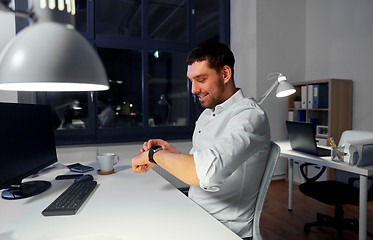 Image showing happy businessman using smart watch at nigh office