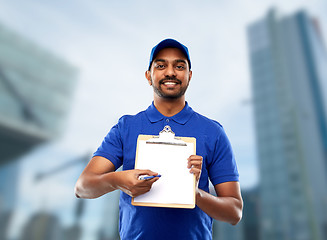 Image showing happy indian delivery man with clipboard in blue