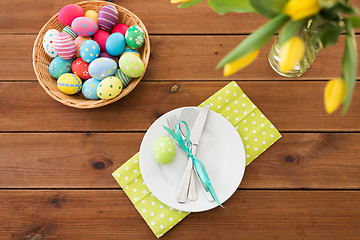 Image showing easter eggs in basket, plates, cutlery and flowers