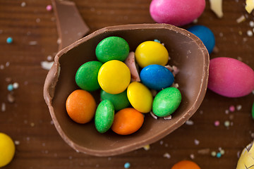 Image showing chocolate egg and candy drops on wooden table