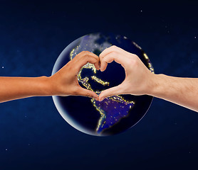 Image showing hands showing heart gesture over earth in space