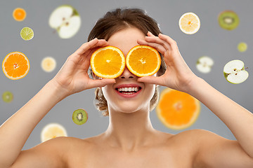 Image showing smiling woman with oranges on eyes over fruits