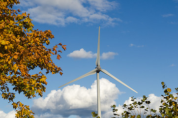 Image showing Windmill by a blue sky and fall colored leaves