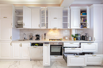 Image showing Luxury modern white kitchen interior with open doors and drawers